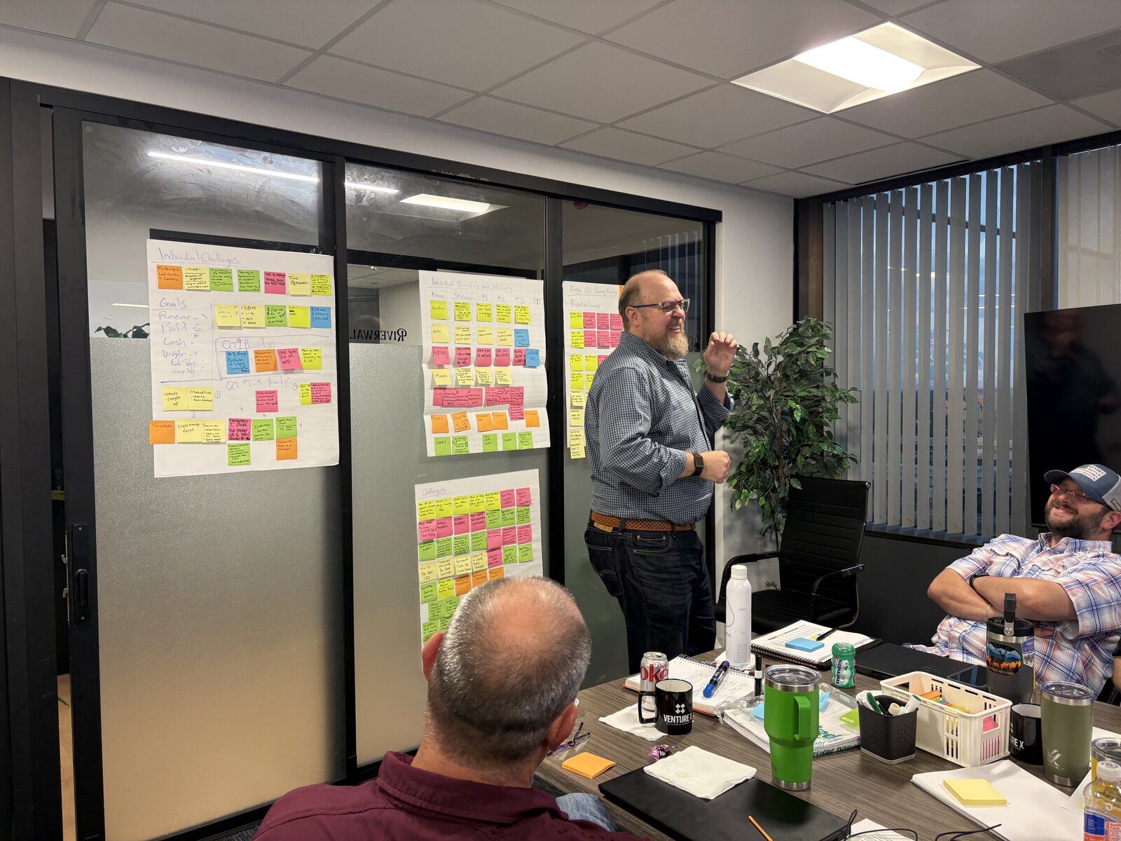 Max Koz at the front of the room with a client team and a wall of sticky notes